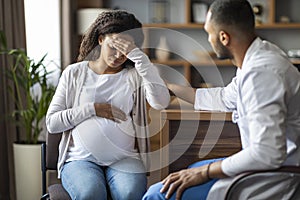 Pregnant black woman feeling bad, visiting doctor at clinic