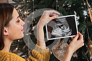 Pregnant young cute girl decorates the Christmas tree