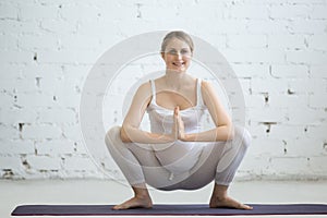 Pregnant young woman doing prenatal yoga. Garland, Malasana Pose