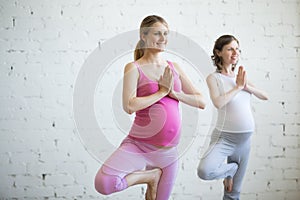 Pregnant young woman doing prenatal yoga. Tree pose photo
