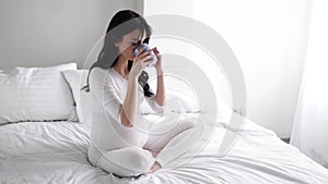 Pregnant Young Woman Drinking Tea And Sitting On Bed At Home