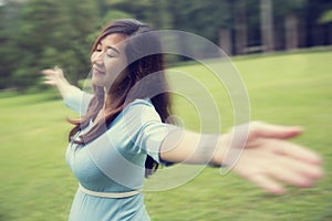 Pregnant young woman enjoying the forest with open arms