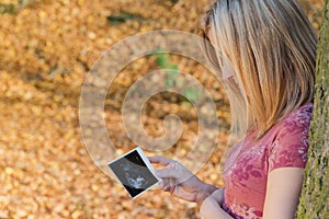 Pregnant young woman is looking at space shot of her unborn child