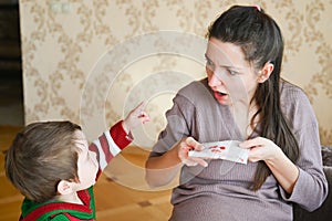 Pregnant young woman scared with nosebleed. A little boy looks at his pregnant mom. Healthcare and medical concept