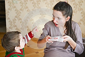 Pregnant young woman scared with nosebleed. A little boy looks at his pregnant mom. Healthcare and medical concept photo