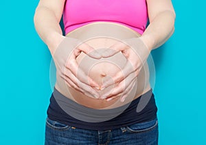 Pregnant young woman showing heart shape with hands