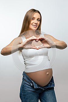 Pregnant young woman showing heart sign and smiling nicely