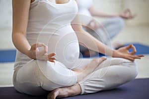 Pregnant young women doing prenatal yoga. Close-up of torso