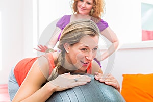 Pregnant young women getting backrub with spiky massage ball