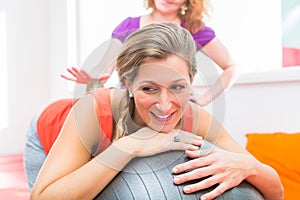 Pregnant young women getting backrub with spiky massage ball