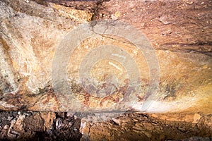 Prehistoric painting of men in actions on rock painted with red colour by human who live in the area over thousand year ago.