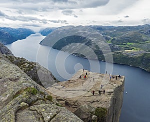 Preikestolen massive cliff at fjord Lysefjord, famous Norway viewpoint with group of tourists and hikers.Moody autumn