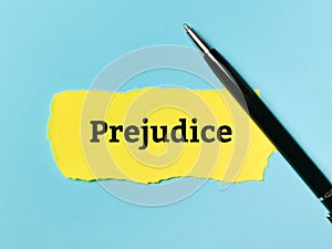 Prejudice written on yellow paper strip with a pen.