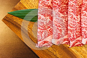 Premium Rare Slices Wagyu A5 beef with high-marbled texture on square wooden plate served for Sukiyaki and Shabu