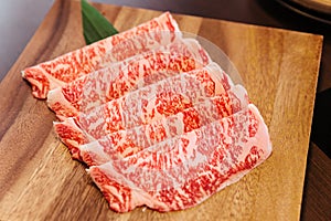 Premium Rare Slices Wagyu A5 beef with high-marbled texture on square wooden plate served for Sukiyaki and Shabu