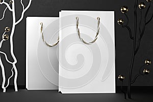 Premium white shopping bags mock-up, package for purchases on a black background. White paper shopping bag with golden