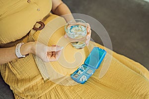 Prenatal Vitamins. Portrait Of Beautiful Smiling Pregnant Woman Holding Pill Box and a glass of water, Taking