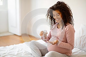 Prenatal Vitamins. Smiling Black Pregnant Woman Holding Pills And Glass Of Water,