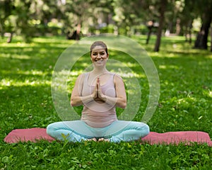 Prenatal yoga. Caucasian pregnant woman doing butterfly pose in the park.