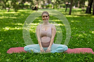 Prenatal yoga. Caucasian pregnant woman doing butterfly pose in the park.