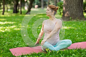 Prenatal yoga. Caucasian pregnant woman doing butterfly pose in the park.