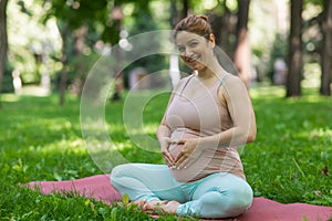 Prenatal yoga. Caucasian pregnant woman doing butterfly pose in the park.