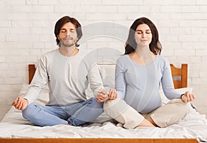 Pregnant woman doing yoga breathing exercises together with her husband