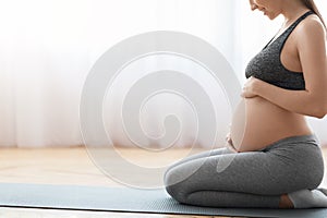 Prenatal Yoga. Smiling Pregnant Woman Sitting On Fitness Mat And Touching Belly