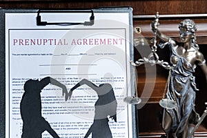 A prenuptial agreement with a silhouette of a couple on a clipboard, with the statue of justice in the background