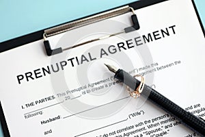 Prenuptial agreement and wedding ring on table. Premarital paperwork process