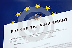 Prenuptial agreement and wedding ring on table. Premarital paperwork process in europe