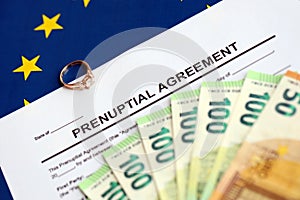 Prenuptial agreement and wedding ring on table. Premarital paperwork process in europe