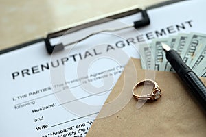 Prenuptial agreement and wedding ring on table. Premarital paperwork process in USA