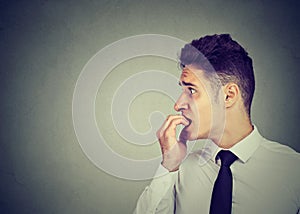 Preoccupied anxious man biting his fingernails looking to the side