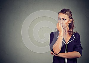 Preoccupied anxious woman biting her fingernails looking to the side photo
