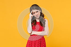 Preoccupied puzzled young brunette woman girl in red summer dress posing isolated on yellow background studio portrait