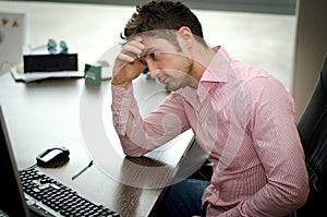 Preoccupied, worried young male worker staring at computer
