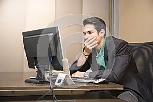 Preoccupied, worried young man staring at computer