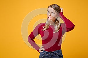 Preoccupied young blonde woman girl in casual clothes posing isolated on yellow orange wall background studio portrait