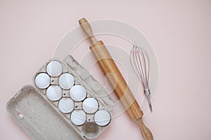 Preparation for baking. Cassette of eggs, rolling pin and whisk on a light background. Kitchen layout