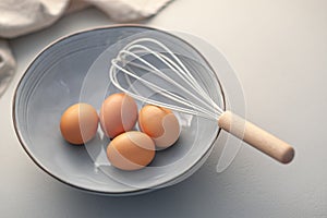 Preparation for Baking With Eggs and Whisk in a Ceramic Bowl on a Kitchen Counter
