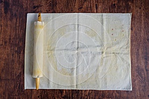 Preparation for baking, well used pastry cloth and covered wooden rolling pin on a wood table