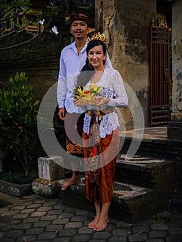 Preparation for Balinese ceremony. Multicultural couple preparing for Hindu religious ceremony with god`s offerings. Caucasian