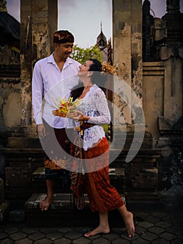 Preparation for Balinese ceremony. Multicultural couple preparing for Hindu religious ceremony with god`s offerings. Caucasian