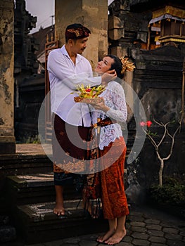 Preparation for Balinese ceremony. Multicultural couple preparing for Hindu religious ceremony with god`s offerings. Caucasian