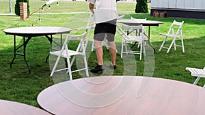 Preparation of a banquet on a green lawn. Worker Arranging chairs for an Event. . Minsk, Belarus - August 15, 2022