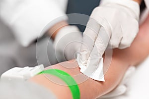 Preparation for blood sampling, patient with a tourniquet band and swab on the arm