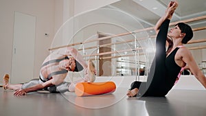 Preparation of body before performance in ballet studio. Male handsome dancer and beautiful ballerina in sports clothing