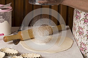 Preparation of bread dough. Bakery, flour is poured, flying flour. clapping and sprinkling flour over dough on table