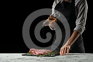 Preparation of the chef by steak cook.Preparation of fresh beef or pork. Horizontal photo with dark black background.